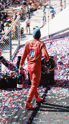 a man in a race suit walking through confetti