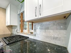 a stove top oven sitting inside of a kitchen next to white cabinets and counter tops