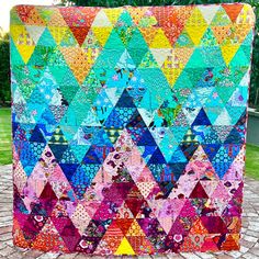 a large colorful quilt sitting on top of a brick floor