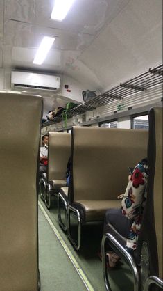 people sitting on seats in an empty train car with no one around them or looking at the camera