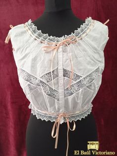 This Edwardian-style corset cover is made in 100% cotton voile. It is trimmed with lace insertion, creating a diamond pattern across the chest. The fronts are gathered at the waist, to create that pigeon bust effect so prevalent of the period. At the back, it has eight small darts to give some shape. At the neckline in front and the armsyce on the back it is trimmed with very fine pintucks. The neckline, waistline and armholes are trimmed with beading lace, so they can be drawn and adjusted. It Underbust Lace Bodice With Lace Trim, White Underbust Bodice With Lace Trim, Vintage Lace Corset With Lace Trim, Vintage Lace Overbust Bodice, Feminine Underbust Corset With Lace Trim, Sleeveless Lace Trim Vintage Corset, Vintage Lace Trim Sleeveless Corset, Vintage Sleeveless Lace Trim Corset, White Vintage Corset With Lace Trim