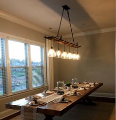 a dining room table is set with place settings for six people and the lights are hanging from the ceiling