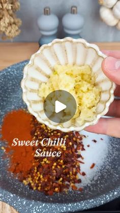 someone is holding up a small bowl filled with spices and seasoning on a plate