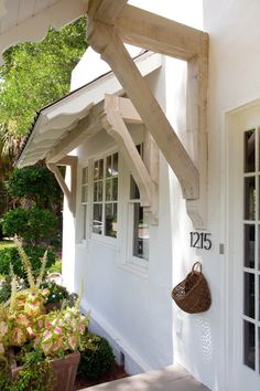 a white house with wooden beams and a basket hanging from the front door, on instagram