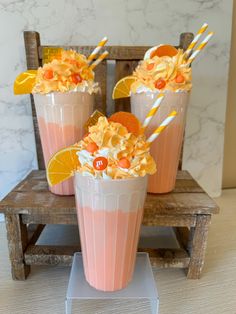 three glasses filled with orange juice and topped with whipped cream, candy canes and candies