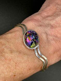 ❤Silver Plated  Cuff Bracelet with 13 x 18 mm Oval Cabochon ❤This dichroic cabochon on this bracelet is 13 x 18 mm.  The cabochon was made with multiple layers of dichroic glass, hand shaped with a diamond blade and glass grinder and fired multiple times in the kiln.  The pendant has a base layer of black and has vibrant dichroic colors of pinks, blue, green and gold dichroic shimmers.   ❤Dichroic glass is produced by stacking layers of glass and micro layers of Quartz Crystal and Metal Oxides (which are vaporized in a vacuum chamber and then applied to the surface of glass in multiple layers) to create decorative glass with shifting color structures. ❤It is difficult to capture the true beauty of Glass in photos. Dichroic Glass changes colors with different lighting and different angles, Unique Oval Cuff Bracelet For Gift, Unique Silver Bracelet With Cabochon, Oval Sterling Silver Cuff Bracelet Gift, Silver Cabochon Cuff Bracelet Gift, Handmade Silver Cuff Bracelet As Gift, Handmade Silver Cuff Bracelet For Gift, Nickel-free Silver Cuff Bracelet, Iridescent Bangle Jewelry For Gifts, Silver Sterling Silver Cuff Bracelet With Cabochon