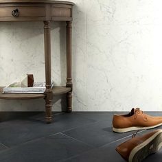 a pair of brown shoes sitting on the floor next to a table with a magazine