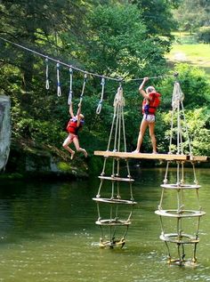 two people are walking across a rope bridge over a river while another person is on the other side