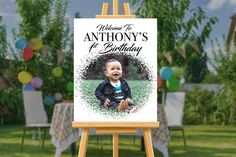 an easel with a photo of a baby on it and balloons in the background