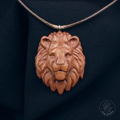 a wooden lion head pendant on a black shirt with a rope necklace attached to it