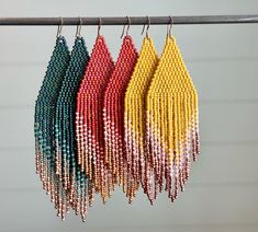 four pairs of beaded earrings hanging from a hook