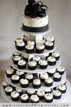 a three tiered wedding cake with cupcakes on the bottom and black bows on top