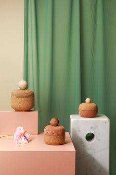 three wooden containers sitting on top of a pink table next to a white vase and flower