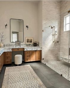 a large bathroom with marble counter tops and wooden cabinets, along with a walk in shower