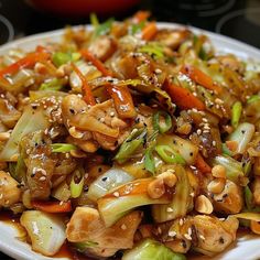 a white plate topped with chicken and vegetables covered in sesame seed sauce on top of a table