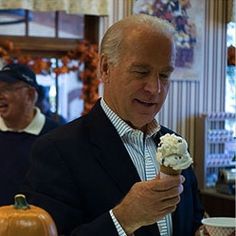 an older man eating ice cream in front of two other men with pumpkins on the table