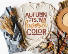 🍁 Autumn is my favorite color, and now it's my favorite shirt, too! 🍂🍃 This cozy tee is perfect for all you fall lovers out there who can't get enough of those golden leaves and pumpkin spice vibes. 🍁 Grab yours today and show off your love for the best season of the year! Bella and Canvas, light weight unisex tshirt. #AutumnIsMyFavoriteColor #FallVibes #CozySeason #BootsandRootsApparel #Momprenuer #ShopSmall #FallFashion #TeeTime #BootsandRootsApparelCo #SupportSmallBusiness #GraphicTees 🍂 Brown Letter Print T-shirt For Fall, Trendy Brown T-shirt For Fall, Lake Girl, Blank Apparel, Small Town Girl, Seasons Of The Year, Best Seasons, Unisex Tshirt, Beach Girl