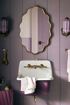 a sink and mirror in a room with wood paneling, purple walls and gold fixtures