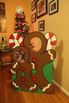 a cardboard gingerbread cutout in front of a christmas tree with pictures on the wall