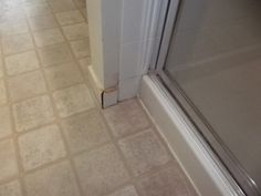 a bathroom with tile flooring and a shower in the corner, next to a door