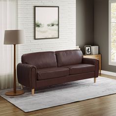 a brown leather couch sitting on top of a hard wood floor next to a lamp