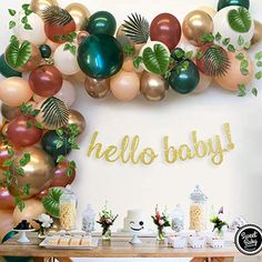 a table topped with lots of balloons and greenery