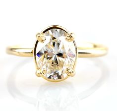 a yellow gold engagement ring with an oval cut diamond in the center, on a white background