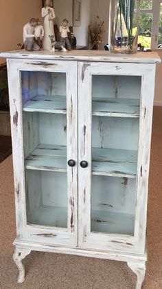 an old white painted cabinet with glass doors