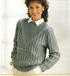 a woman wearing a sweater and white pants with her hands on her hips, posing for the camera