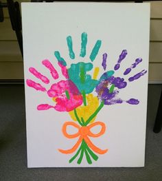 handprints on a white card with orange ribbon and bow in front of it