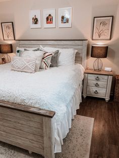 a white bed sitting in a bedroom next to two lamps and pictures on the wall