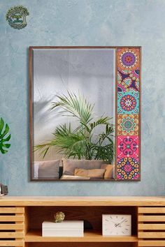 a mirror sitting on top of a wooden shelf next to a plant in a vase