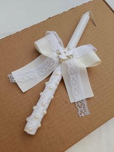 a white ribbon with pearls on it and a candle in the middle is laying on top of a cardboard box