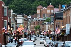 a city street filled with lots of traffic next to tall red brick buildings and trees