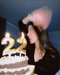 a woman is blowing out the candles on her birthday cake that has been decorated with chocolate and white frosting