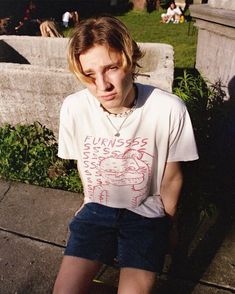 a young man sitting on top of a cement bench