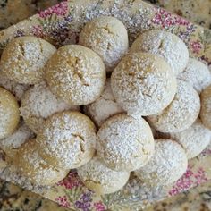 a bowl filled with powdered sugar cookies on top of a table