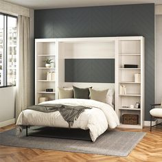 a white bed sitting next to a window in a bedroom under a book shelf filled with books