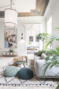 a living room filled with furniture and lots of plants on the floor in front of a painting