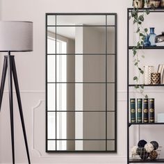 a large mirror sitting on top of a wall next to a shelf filled with books