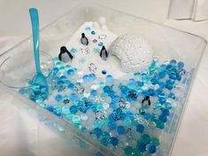 a plastic container filled with lots of blue and white beads next to a snowman