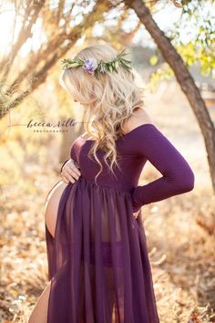 a pregnant woman wearing a purple dress and flower crown in her hair is looking at the camera