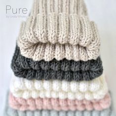 a stack of knitted hats sitting on top of each other in different colors and sizes