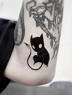 a black cat tattoo on the left side of the leg, with an arrow in the middle