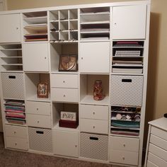 a white bookcase filled with lots of different types of books and binders on top of it