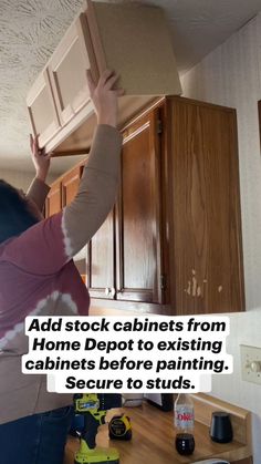 a woman is lifting cabinets from the ceiling in her kitchen, with text overlay that reads, add stock cabinets from home depot to existing cabinets before painting, secure to studs