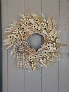 a wreath is hanging on the side of a door with dried flowers and leaves around it