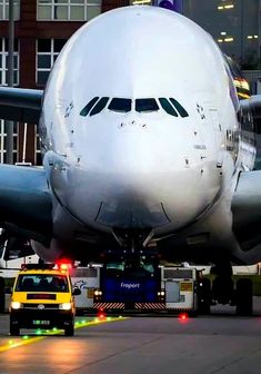 an airplane that is sitting on the tarmac with its lights on and emergency vehicles around it