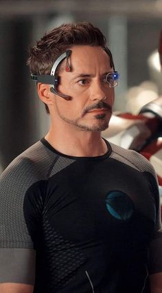 a man in a black shirt with glasses on his head and an iron man behind him