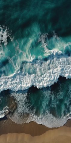 an aerial view of the ocean waves and sand